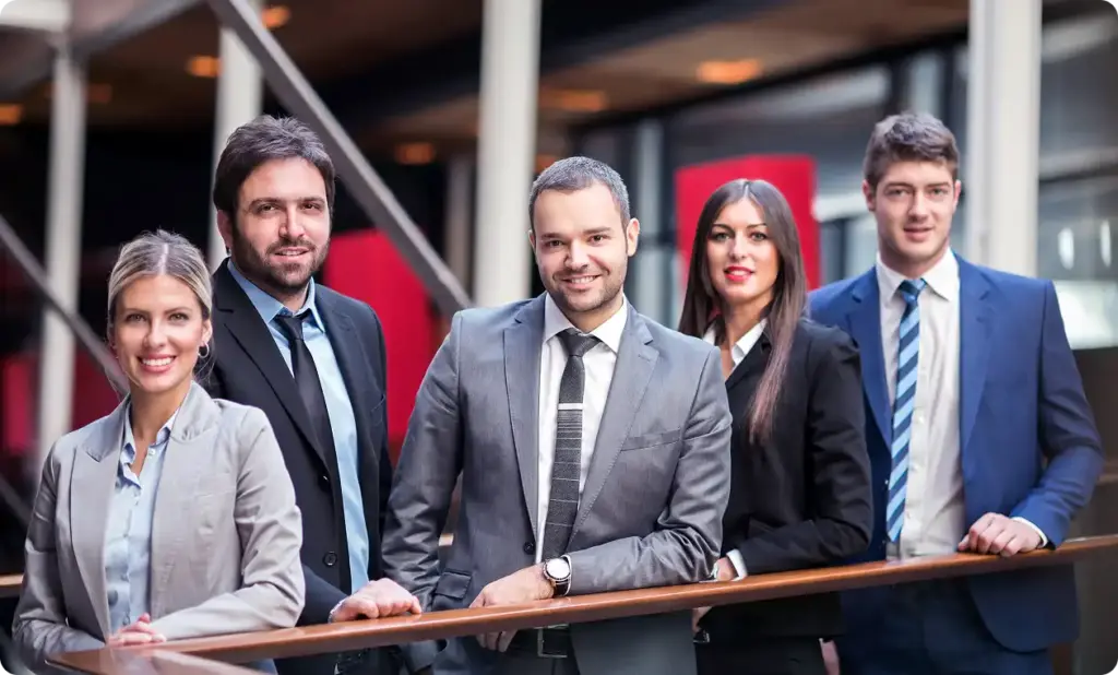 Grupa ludzi biznesu w garniturach stoi w nowoczesnej przestrzeni biurowej.