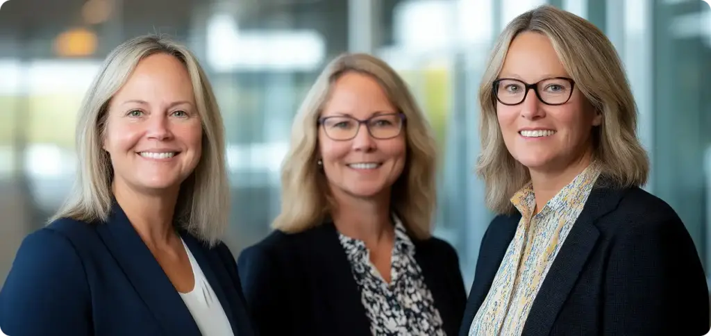 Trzy kobiety biznesu w biurze patrzą w kamerę, ubrane w surowe kostiumy.