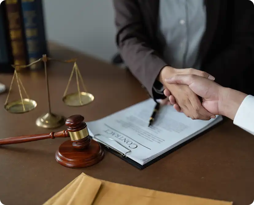 Prawnik i klient ściskają sobie dłonie nad podpisanym kontraktem.