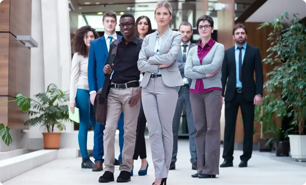 Grupa pewnych siebie biznesmenów idzie przez nowoczesny hol biurowy w kierunku kamery.
